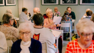Senioritalo Cecilian asukkaat laulavat yhdessä Rastilan kartanon salissa.